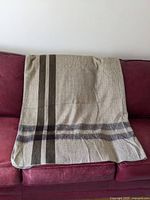 Brown alpaca blanket folded over a couch, showing the large size and stripe pattern.
