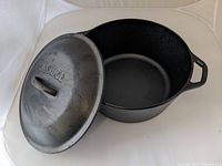 Lodge cast iron pan with lid resting open showing interior and lid with embossed brand.