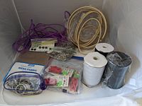Photo showing wooden embroidery hoops, elastic on spools, purple cord, black buttons, metal rings, and bagged red clips.