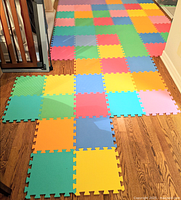 Full view of assembled colorful interlocking foam squares laid on hardwood floor, showing size and layout with multiple colors