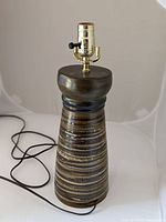 Full view of the handmade ceramic lamp showing conical striped ceramic base and electrical cord.