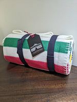 Rolled blanket on wood surface showing colored stripes and navy straps