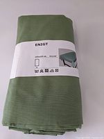 Front view of the folded green Ikea Enigt tablecloth with product label showing dimensions and care symbols.