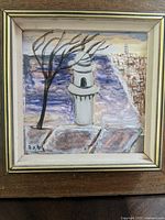 Close-up of framed painting showing a town scene with a tower, barren tree, and background cityscape.