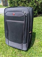 Front view of large black SwissGear suitcase with Swiss cross logo on front pocket.