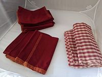 Photo of folded red napkins stacked next to folded checked tablecloth showing color and pattern