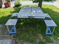 Photo of the picnic table set up outdoors on grass showing the rectangular table with four attached seats.