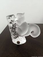 Side view of the frosted crystal squirrel perched on a textured clear crystal tree branch with the Reijmyre Kristall label visible on the base.