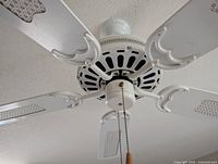 Close-up of white ceiling fan without light fixture, showing motor housing and four blades with ventilation slots.