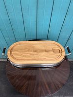 Full view of the assembled serving tray with silver plated base and the oak wooden insert on top, showing metal handles and oval shape.