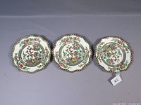 Set of three Coalport Indian Tree plates shown laid on surface with scalloped edges and floral design in center.