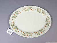 Top-down photo showing the entire oval platter with strawberry and floral pattern along scalloped edge on a white background.