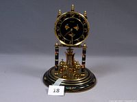 Full view of black base and clock face with floral designs, showing two supporting columns and missing dome