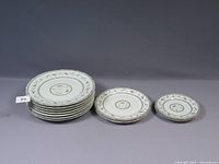 Top view of stacked plates showing 7 dinner plates, 2 luncheon plates, and 2 side plates with floral blue and red design and gold trim.