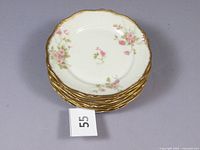 Stack of 8 Limoges porcelain plates with pink floral design and gold rims showing the overall lot