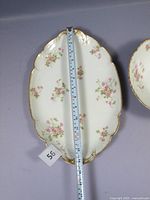 Oval platter with floral design and gold edge, measuring approximately 12 inches, placed flat with a measuring tape