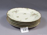 Stack of 5 Limoges plates with purple floral pattern and gold trim showing side profile and edge wear