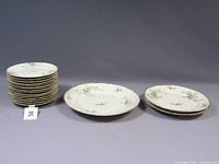 Full view of stacked salad and bread plates alongside two dinner plates front-facing showing floral pattern and gold trim.