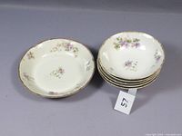 Stack of five matching cereal/soup bowls with purple floral pattern and gold trim