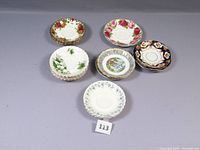 Photo showing seven Royal Albert saucers in various floral patterns arranged in a hexagonal shape with one in center, displayed on a gray surface.