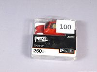 Clear plastic packaging showing Petzl Tikkina 250 lumens headlamp with red headband and white light casing, labeled with product branding and brightness.