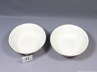 Top view of two white porcelain serving bowls with scalloped edges and gold trim, placed side by side.
