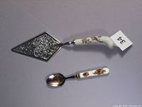 Photo showing the full view of the cake server and spoon, displaying the floral porcelain handles and embossed metal blade of the cake server.