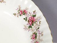 Close-up of one of the serving bowls showing pink rose floral pattern with gold rim