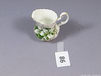 Royal Albert Trillium creamer shown from side angle, displaying floral design and gold accents.