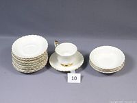 Full set of one tea cup with saucer, multiple extra saucers and four fruit bowls arranged for display