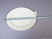 Front view of the oval white bone china serving platter with gold rim.