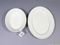 Top view image showing the white bone china serving bowl and platter with scalloped edges and gold rims on a gray background.