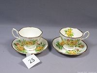 Two Royal Albert Yellow Tea Rose porcelain tea cups and matching saucers arranged side by side showing the side and front profile