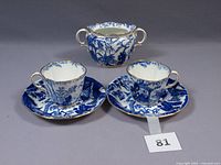 Two Royal Crown Derby Blue Mikado cups and saucers with matching sugar bowl shown from front.