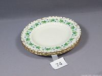 Four stacked salad plates with maple leaf and blue grapevine pattern and gold edging.