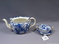 Side view of teapot showing crack and missing lid, and cream soup bowl with underplate beside it