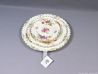 Stack of nine Royal Crown Derby Posies plates, showing floral decoration and gold trim, from top view