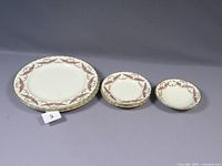 Full set of eight items showing four large dinner plates, three smaller plates, and one bowl with pink fern leaf and gold rim pattern.