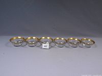 Six clear glass dessert bowls in a row, showing gold rims and overall vintage condition.