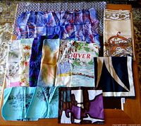 12 scarves arranged on table showing a variety of colors and patterns including floral, cityscapes, and abstract designs.