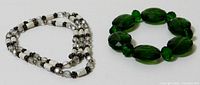 Two bracelets shown together, white magnetic and green faceted bead bracelet