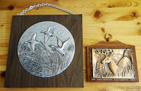 Two Canadian wildlife-themed wallhangings on a wooden surface; larger one with ducks and smaller one with deer.