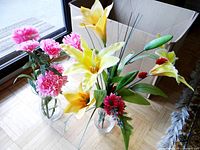 Two glass vases with bright artificial flowers, showing both sets of flowers and vases.