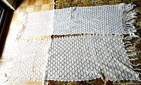 Both Haapsalu scarves laid flat side by side on floor, showing off-white and white colors, lace patterns, and fringes.