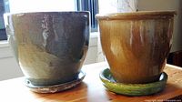 Both terra cotta flower pots together showing color contrast and saucers