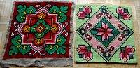 Two needlepoint cushion covers side by side on wooden floor, showing colorful floral geometric patterns