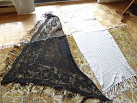 Both shawls laid out flat on a patterned carpet in natural light showing full lengths and fringes.