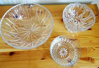 Three etched and cut glass bowls displayed on wooden surface: largest with starburst and elongated tear-drop cuts; middle lead crystal Imperlux with diamond etching and label; smallest with starburst and diamond cut design.