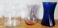 Three large glass vases side by side showing their relative sizes and colors (clear, pale pink, dark blue)