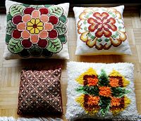 Four handmade cushions arranged on floor showing different embroidered and textured designs